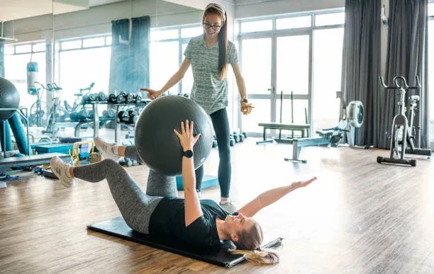 A trainer guiding a client through an exercise on the apparatus